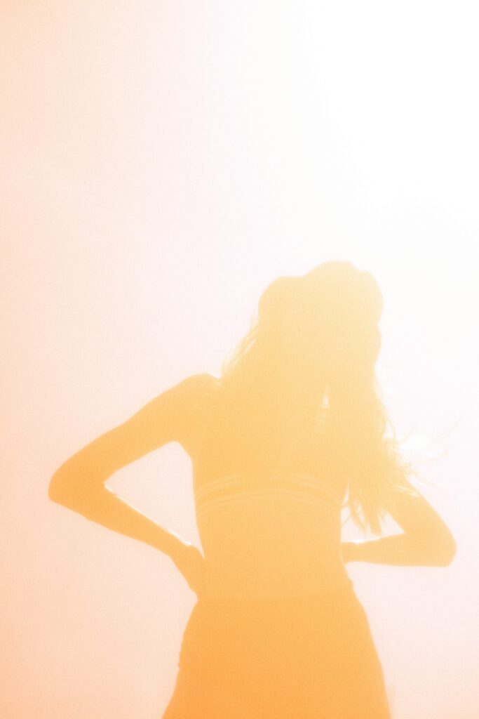 Femme debout en pleine conscience, entourée d'une lumière douce représentant l’énergie corporelle et la puissance du corps